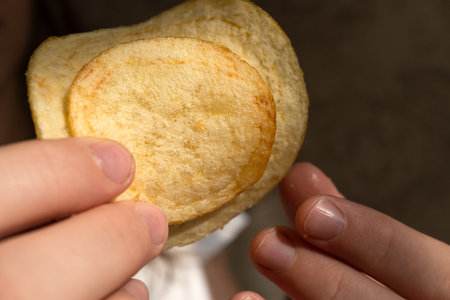 Snack, potato chips close-up in children's hands. Backgroundの写真素材