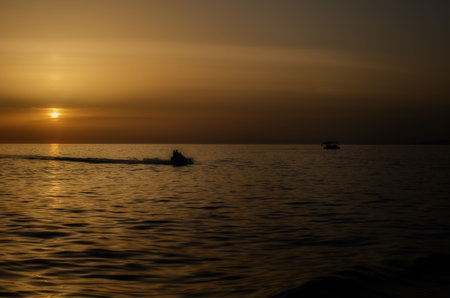 Silhouette of people on jet skis against the backdrop of sunset in the sea or oceanの写真素材