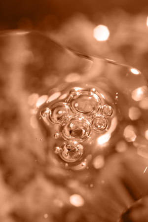 air bubbles and glitter in cosmetic serum on a festive background for advertising and presentation of cosmetic products. Color peach fuzz.の写真素材