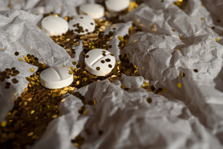 White pills and glitter lie on white packaging paper.の写真素材