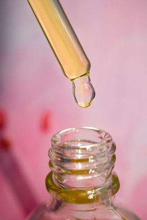 Pipette with essential oil on bottle blurred background