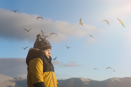 A person stands on the seashore against the backdrop of mountains.の写真素材