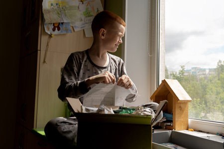 A child cleans his desk and collects waste paper in a box.
