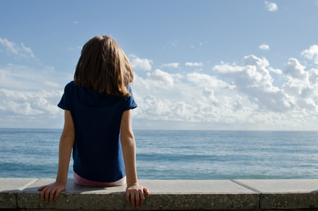 Teen girl walking on the beach and looking at the oceanの写真素材