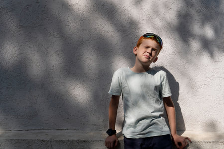 Child near the wall of a house on a summer sunny day with reflexes and shadowsの写真素材