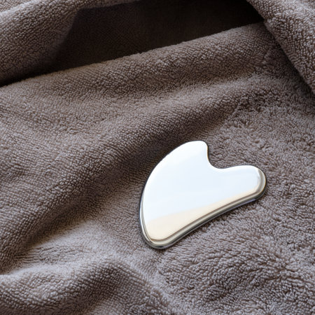 Stainless steel gua sha tool with soft towel, close-upの写真素材
