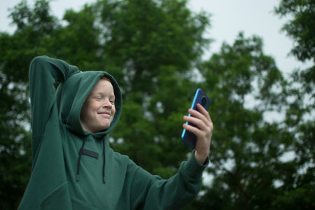 A boy in the park communicates on the phone, takes a selfie on the phoneの写真素材