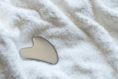 Stainless steel gua sha tool with soft towel, close-upの写真素材