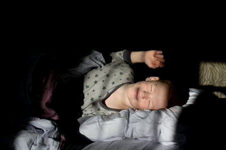 The child wakes up and stretches in the dawn rays of the sunの写真素材