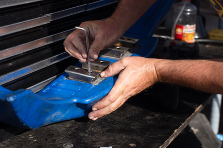 A mechanic adjusts the position of the front bumper on a racing car with a hexagon. Preparation for competitions. Car maintenance at the pit stopの写真素材
