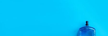Transparent glass cosmetic bottle for perfume on a blue surface. Top view. Background for your...