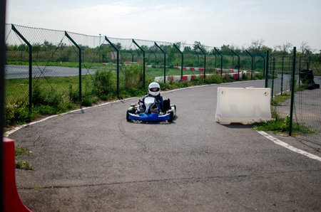 Boy racer in a helmet driving a sports kart. Children's karting competitions on a professional track.の写真素材