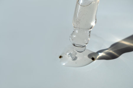 Pipette with essential oil on bottle blurred background