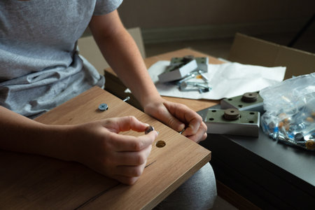 Cropped hand of a child assembling furniture according to instructions, using different tools. Active help around the house, a man's hobby.の写真素材