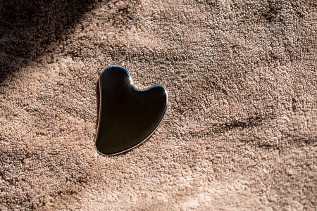 Stainless steel gua sha tool with soft towel, close-upの写真素材