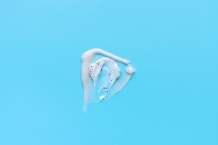 face cream and scrubs on a blue background. Smear of cosmetic product on a light background