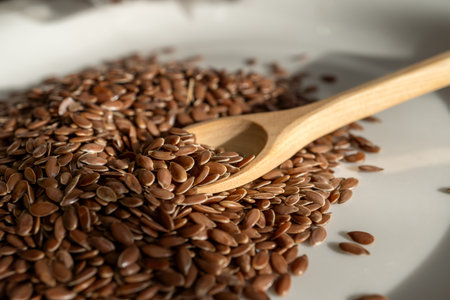 Dried flax seeds on a plate with a wooden spatula are used in cooking as a seasoning.
