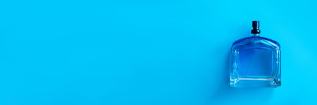 Transparent glass cosmetic bottle for perfume on a blue surface. Top view. Background for your...