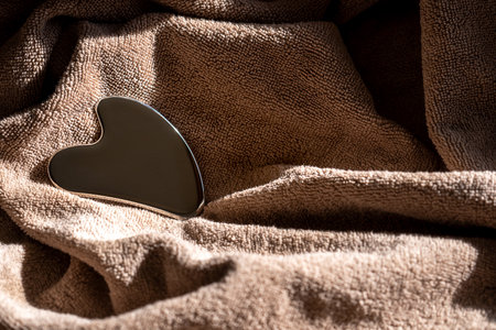 Stainless steel gua sha tool with soft towel in Mocha Mousse, close-upの写真素材