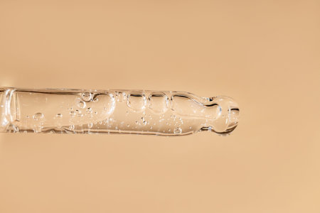 Glass pipette with facial serum on a light background. Essential oil close-up in a pipette. A skin...
