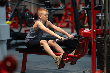 Teenager exercising on Multi-gym machine. Pulldown machine. Cable triceps extension. Weight lifting exercises in the gym.の写真素材