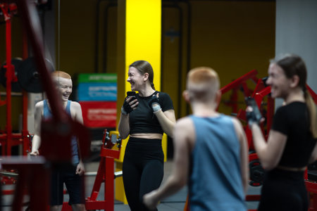 Portrait of young woman and teenager using phone and taking selfie photo while taking break during gym workoutの写真素材