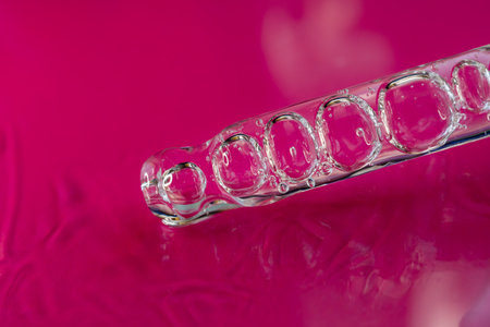 Glass pipette with facial serum on a red background. Essential oil close-up in a pipette. A skin...