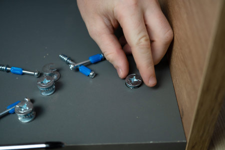 Cropped hand of a child assembling furniture according to instructions, using different tools....
