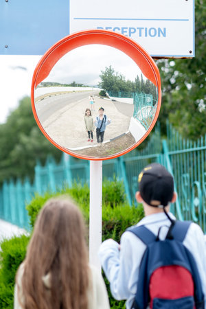 Road mirror, spherical observation at the intersection, reflection of children in the mirror. High quality photo