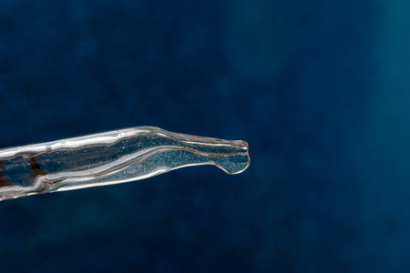 Glass pipette on a light background. Essential oil close-up in a pipette.