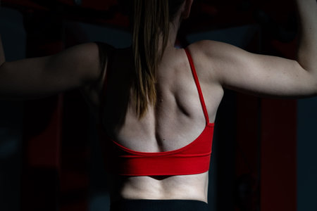 Close-up of womans back flexing muscles in red workout topの写真素材