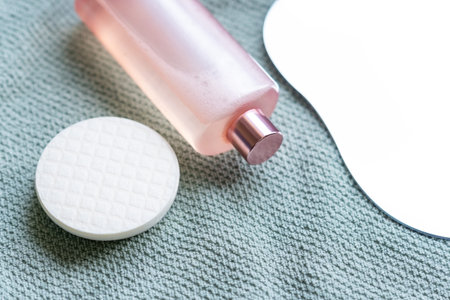 Cosmetic product and reusable cotton pads lie on a towel