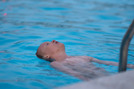 The boy bathes, swims and dives in the pool. Summer vacation and travel concept. Peaceful tropical summer holiday, travel, relaxation, summer vacation,. High quality photoの写真素材