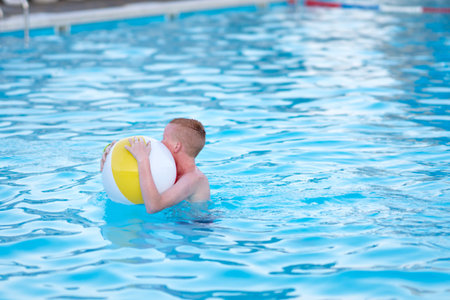 A boy is swimming in a pool on an inflatable ball. Summer vacation and travel concept. Peaceful...