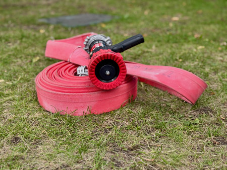 A red water fire hose is lying on the lawn. High quality photoの写真素材
