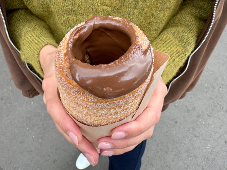 sweet trdelnik with nutella in the hands of a girl in summer. High quality photoの写真素材