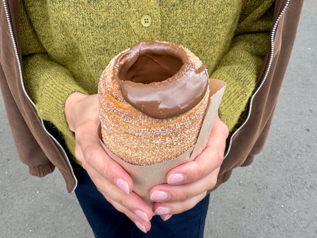 sweet trdelnik with nutella in the hands of a girl in summer. High quality photoの写真素材