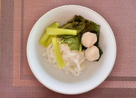 Delicious mouth-watering Asian noodles with meatballs in a white plate on the table. High quality...