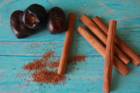 Three dates and sticks of cinnamon close up on a blue background shabby chic. Horizontal photo.の写真素材