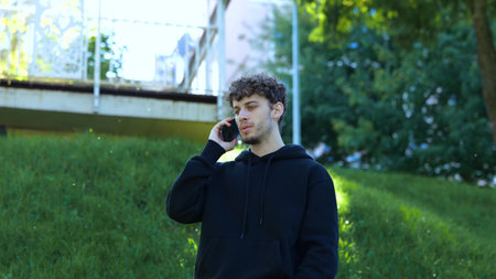 Guy talking on the smartphone and receiving bad news while standing in the city park. Lifestyle....