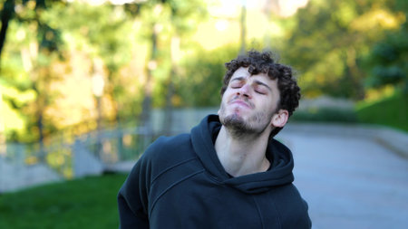 Young Caucasian man feeling pain after working out. Sportsman running in park, feeling leg hurt after outdoor activities. Face of guy showing strong pain.の写真素材
