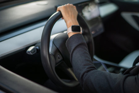 Woman hand on the steering wheel of a car. Smartwatch on businesswoman hand. Cropped. Lifestyle, driving, transport conceptの写真素材