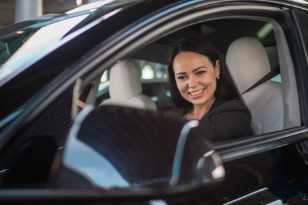 Smiling businesswoman fastened with a seat belt enjoying driving while looking side view mirror. People, driving, transport and lifestyle conceptの写真素材