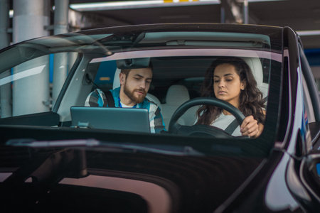 Man is an instructor, controlling and checking while woman passing exam at driving school. Driving test, driver courses, exam conceptの写真素材