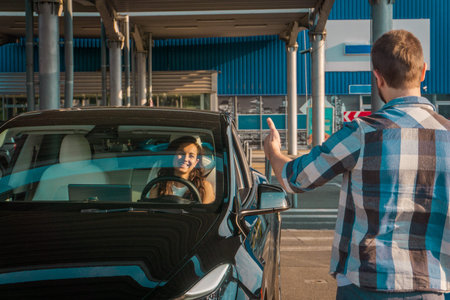 Male instructor showing thumbs up. Lady sitting inside car while passing exams successfully at...