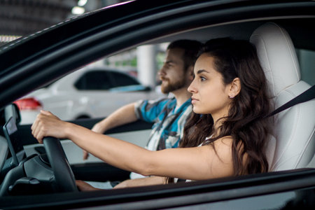 Female driver riding car, young man sitting inside auto on passenger seat. Side view. Travel adventure drive, happy summer vacation conceptの写真素材