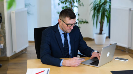Slow motion video. Caucasian businessman in black suit and blue shirt is sitting at the table,...