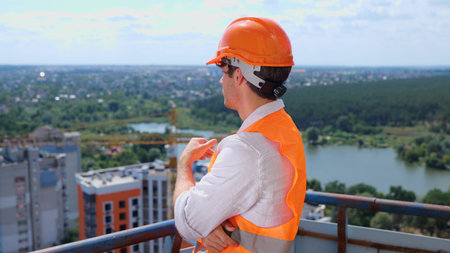 Young male builder standing on the roof of construction site while thinking about new project....