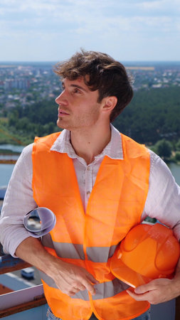 Architect Caucasian man working with drawing while standing in the construction site on the roof. Business, building, industry concept. Slow motionの写真素材