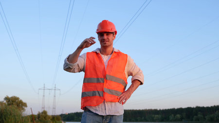 Smiling male engineer in safety helmet working for electric power generation. Highest voltage...